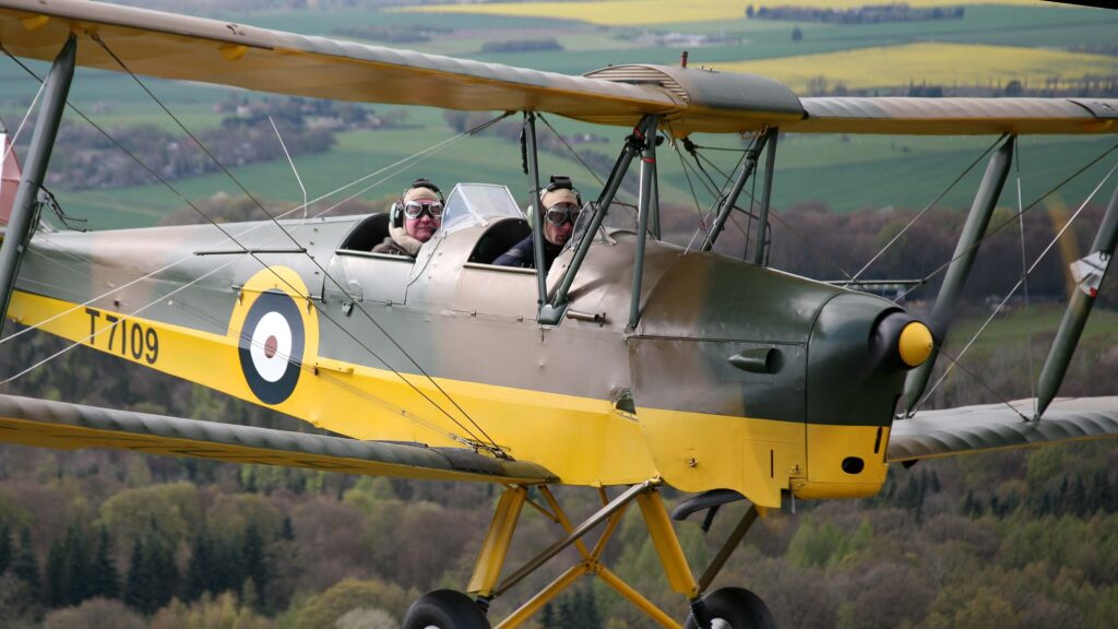 yellow and green Tiger Moth plane with views of the English coutnryside