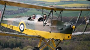 yellow and green Tiger Moth plane with views of the English coutnryside
