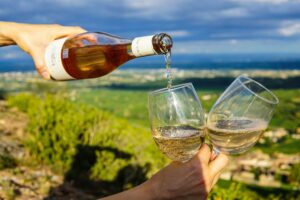 someone puring two glasses of wine in the vineyard