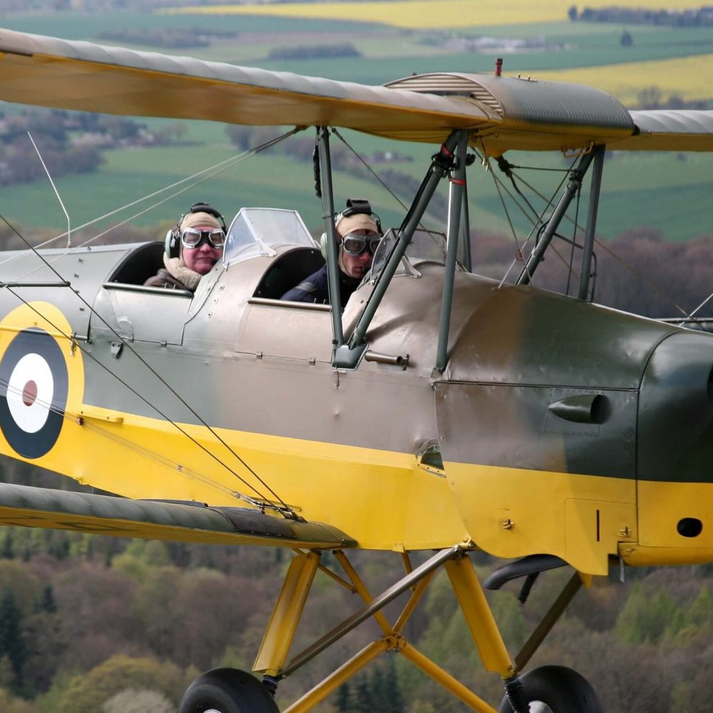 yellow and green Tiger Moth plane with views of the English coutnryside